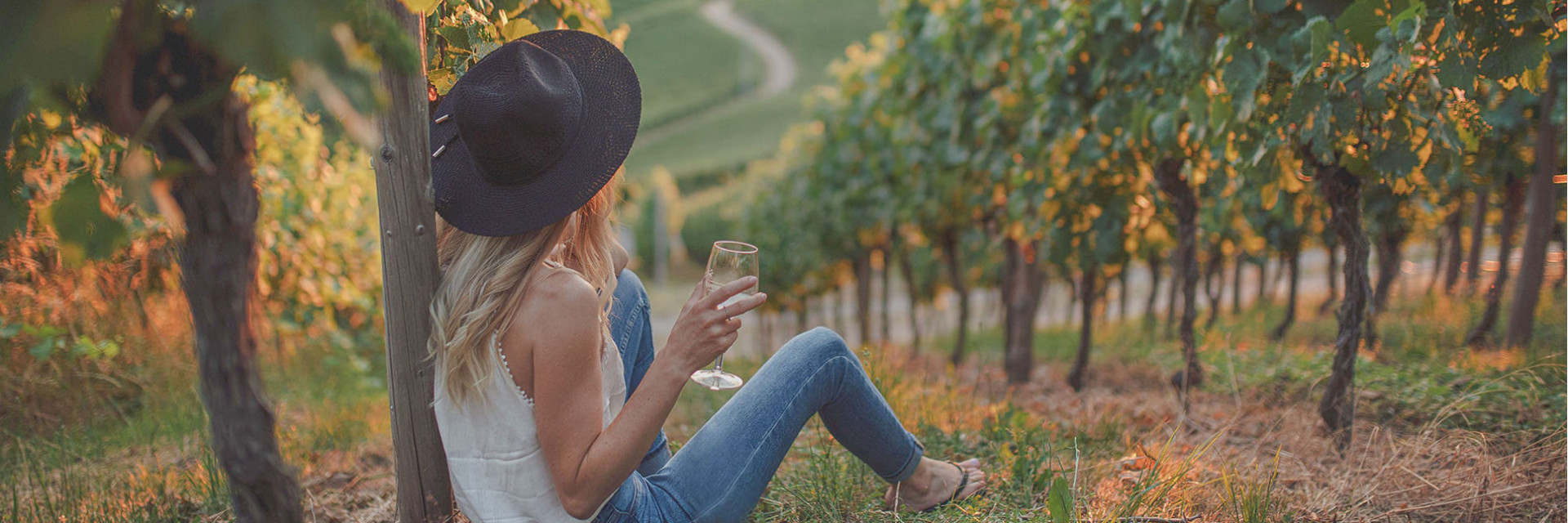Photo of a woman enjoying a glass of white wine at sunset over the vines. Photo of a woman enjoying a glass of white wine at sunset over the vines.