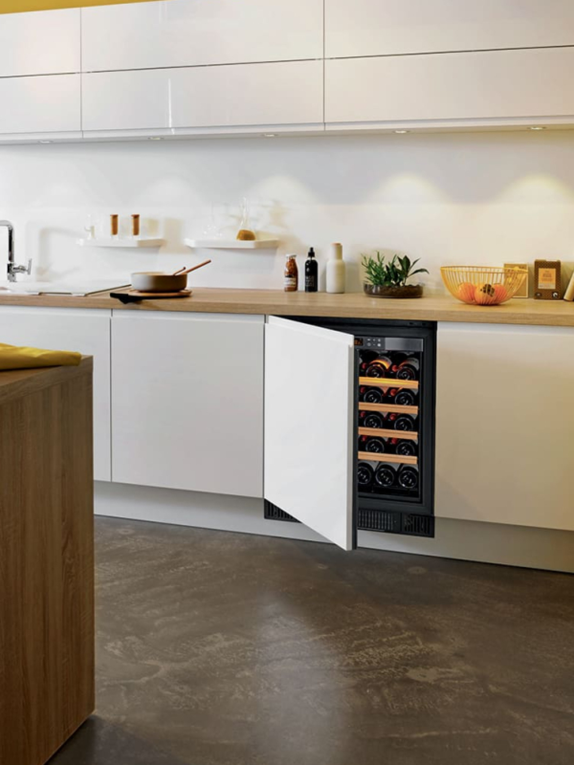 Small wine cooler recessed under a worktop with an opaque technical door with assembly of the front of the cabinet. Full anti-UV door.