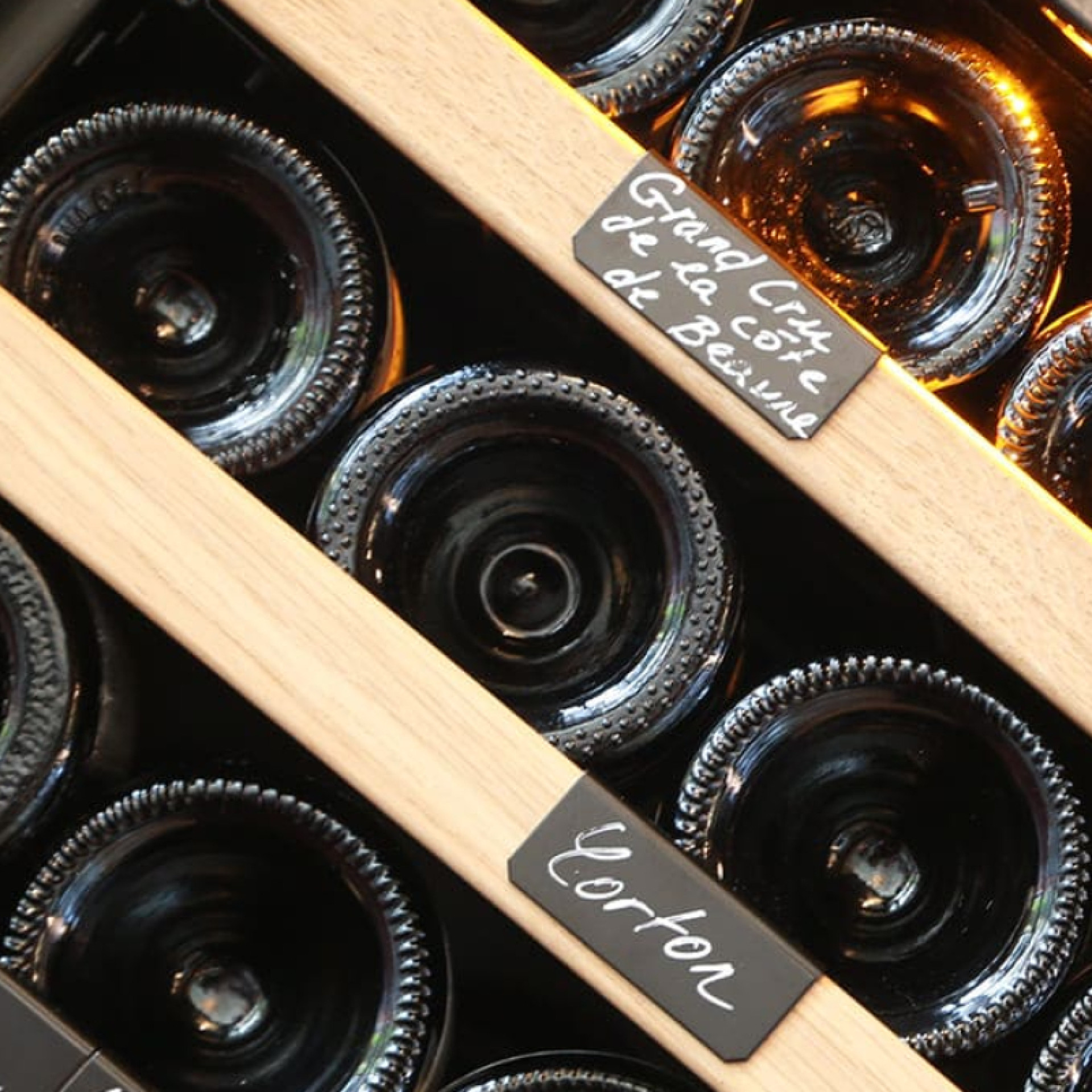 Wine cabinet storage - metal shelves with individual bottle holders, natural-coloured oak wood front.