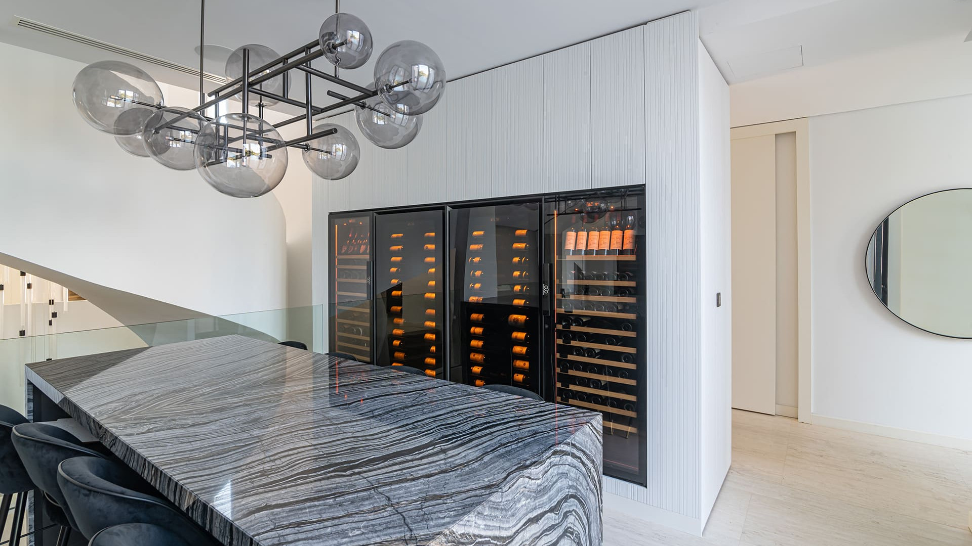 Four wine cabinets built into a custom-made piece of furniture in a residence with prestigious interior architecture. In the foreground a long marble table. - Royale EuroCave Four wine cabinets built into a custom-made piece of furniture in a residence with prestigious interior architecture. In the foreground a long marble table. - Royale EuroCave