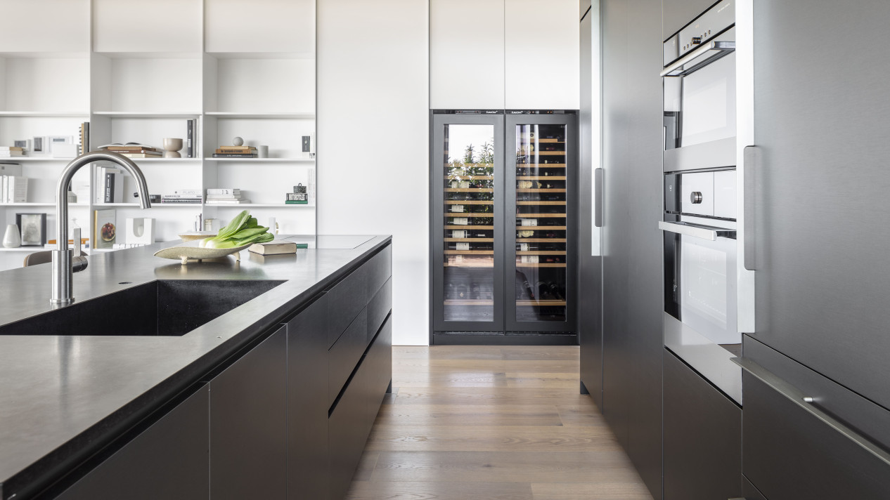 Decorative inspiration. Kitchen renovation. Glazed wine fridge integrated into a made-to-measure kitchen unit with an anthracite gray wooden front to underline and highlight it. Decorative inspiration. Kitchen renovation. Glazed wine fridge integrated into a made-to-measure kitchen unit with an anthracite gray wooden front to underline and highlight it.