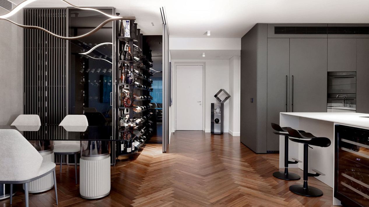 Glass climate controlled wine display integrated into a dining room with open kitchen