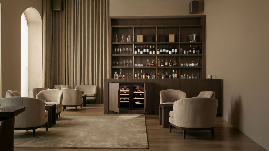 Small EuroCave Compact wine coolers with full technical wood-finish doors, built side by side into a custom dark wood bar unit, in a sleek contemporary interior
