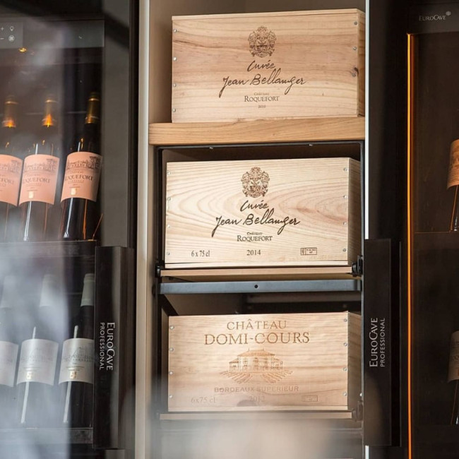 Robust wooden and steel sliding racks for wine storage, designed to hold two cases of 12 bottles while preserving their original wooden cases.