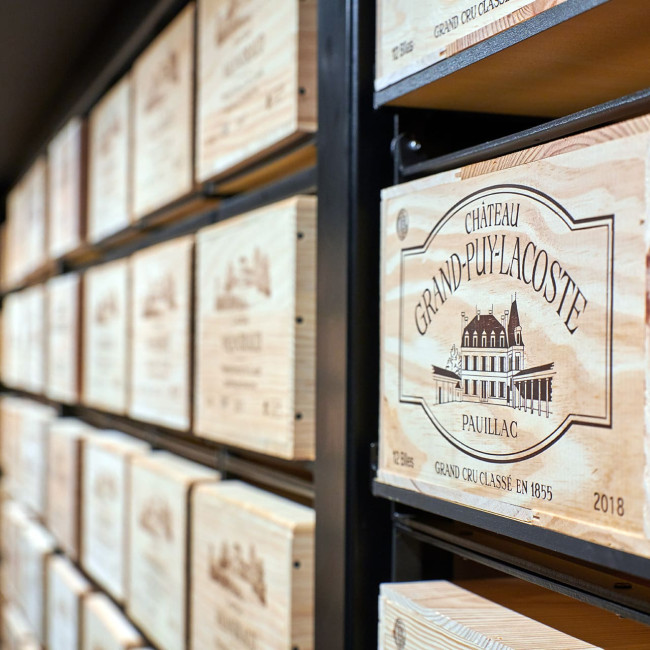 Shelving made up of several assembled Modulorack units, forming a wine wall with wooden crates on a black metal structure, combining an industrial and authentic design.